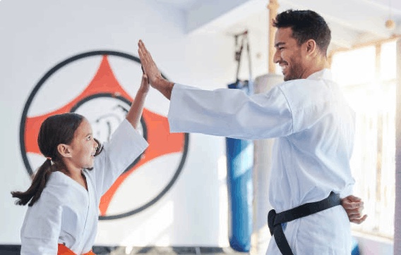 Martial arts instructor high-fiving a young student